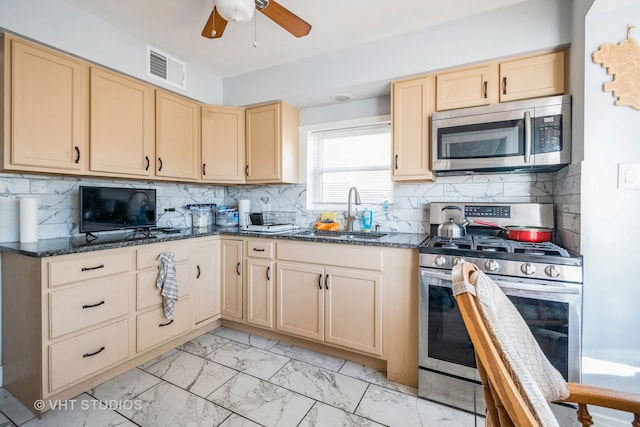 kitchen featuring tasteful backsplash, appliances with stainless steel finishes, sink, dark stone countertops, and ceiling fan