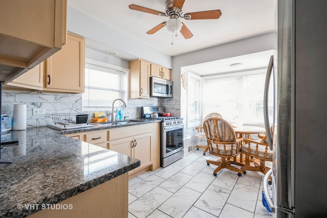 kitchen featuring dark stone counters, light brown cabinets, backsplash, and stainless steel appliances