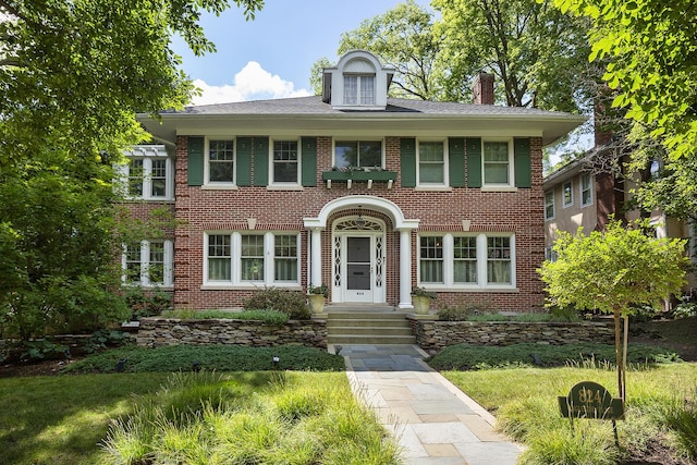 colonial home featuring brick siding and a chimney