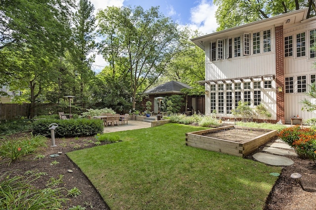 view of yard with a patio, a vegetable garden, and fence