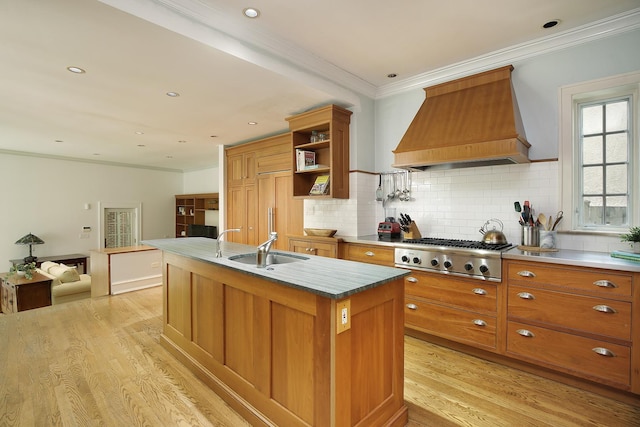 kitchen with stainless steel gas stovetop, light countertops, a center island with sink, and custom exhaust hood