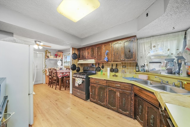 kitchen featuring light hardwood / wood-style floors, a textured ceiling, sink, stainless steel range with gas cooktop, and ceiling fan