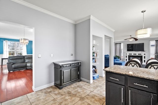 kitchen with ceiling fan with notable chandelier, crown molding, pendant lighting, built in features, and light hardwood / wood-style flooring