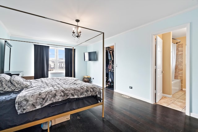 bedroom with a walk in closet, ensuite bath, crown molding, wood-type flooring, and a closet