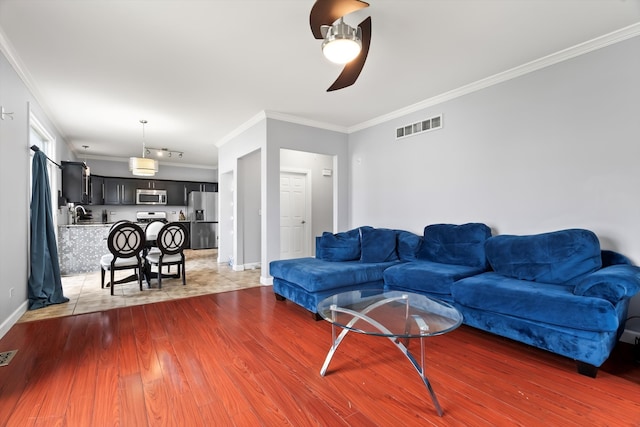 living room with crown molding, ceiling fan, and dark wood-type flooring