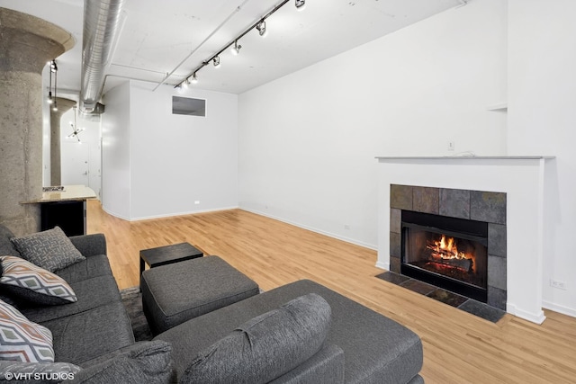 living room with a tile fireplace, hardwood / wood-style flooring, and track lighting