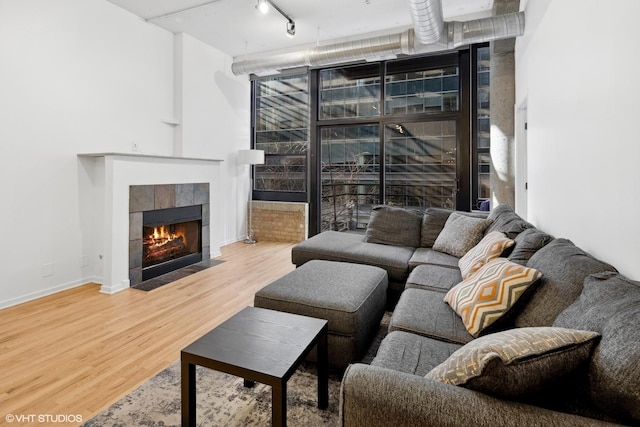 living room featuring rail lighting, hardwood / wood-style flooring, and a tiled fireplace