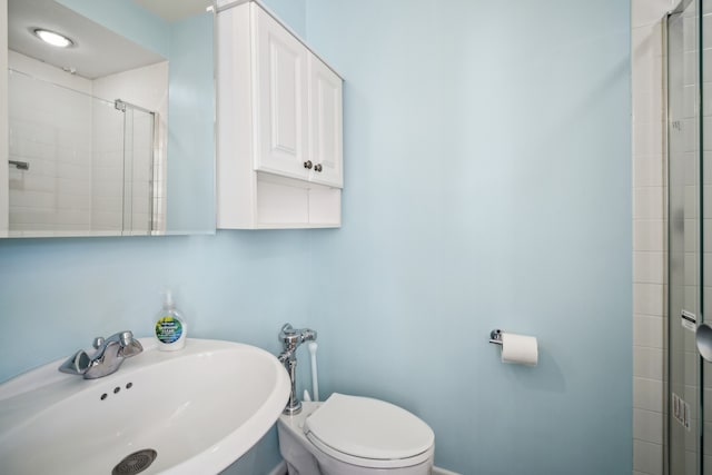 bathroom featuring sink, an enclosed shower, and toilet