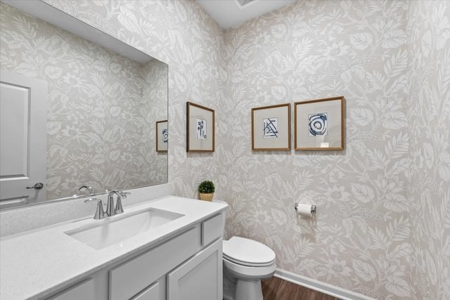 bathroom with toilet, hardwood / wood-style floors, and vanity