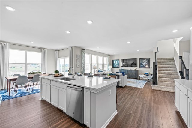 kitchen featuring sink, white cabinetry, stainless steel dishwasher, dark hardwood / wood-style floors, and a kitchen island with sink