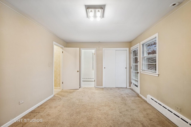 spare room with crown molding, baseboard heating, and light carpet