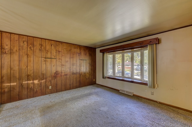 carpeted spare room with wooden walls