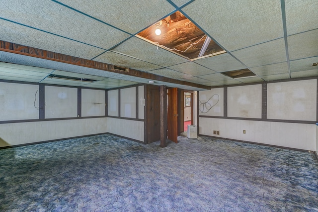 basement featuring a drop ceiling and dark carpet