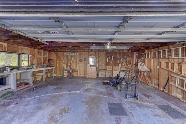 garage with a workshop area, wood walls, and a garage door opener