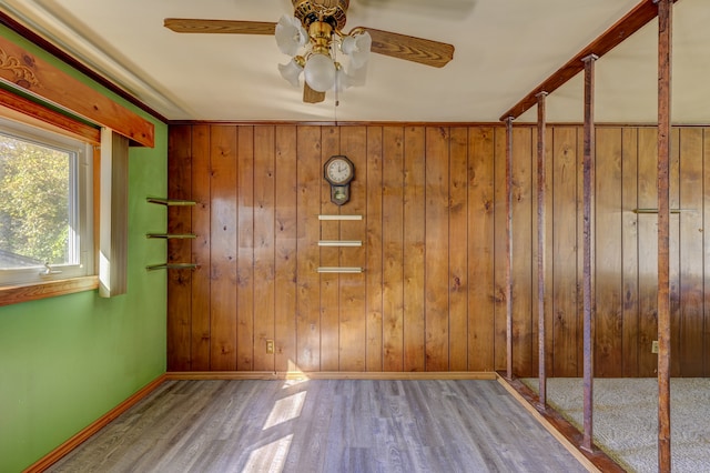 unfurnished room with wooden walls, hardwood / wood-style flooring, and ceiling fan