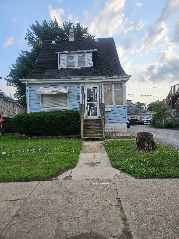 bungalow-style home featuring a chimney, a front yard, and entry steps