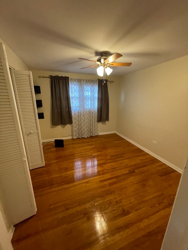 empty room with ceiling fan and dark hardwood / wood-style flooring