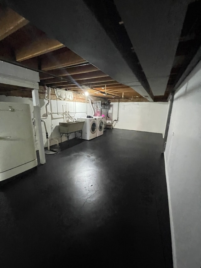 basement with washer and clothes dryer, sink, and refrigerator