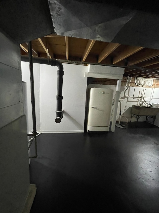 basement with sink and white refrigerator