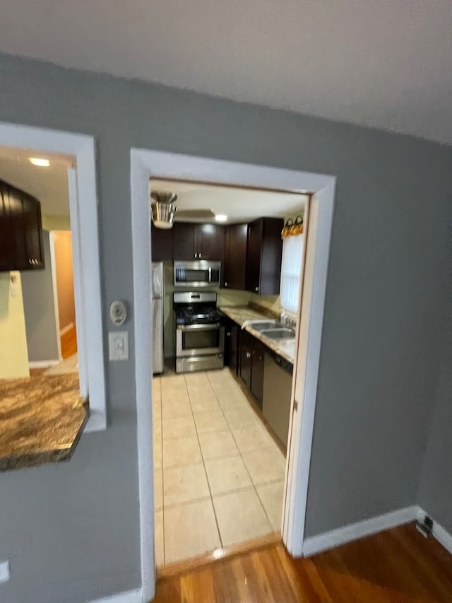 kitchen featuring dark brown cabinets, stainless steel appliances, sink, and light hardwood / wood-style flooring