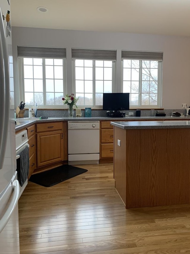 kitchen featuring white dishwasher, wall oven, stainless steel fridge, and plenty of natural light