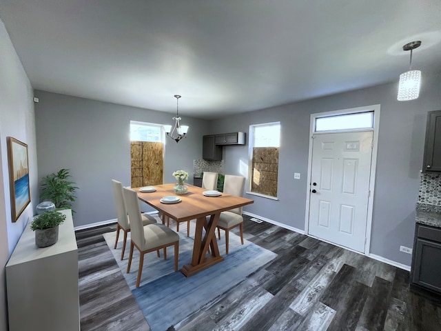 dining area with dark wood-type flooring, a wealth of natural light, and an inviting chandelier