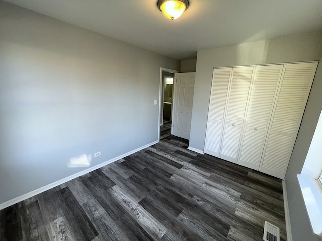 unfurnished bedroom featuring a closet and dark hardwood / wood-style floors