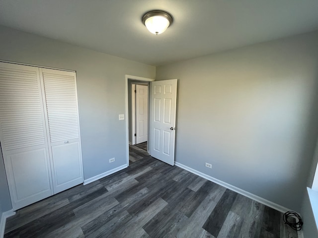 unfurnished bedroom with dark hardwood / wood-style flooring and a closet