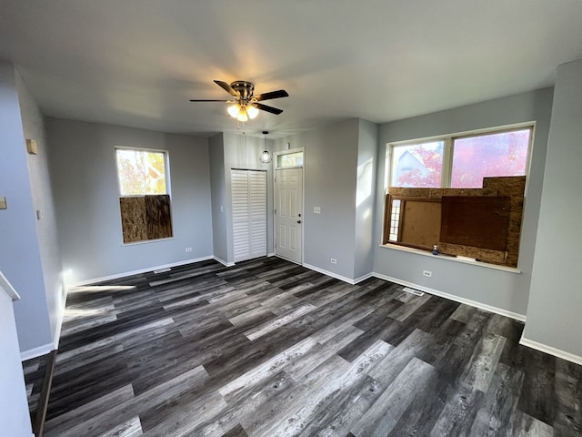 unfurnished living room featuring a wealth of natural light, ceiling fan, and dark hardwood / wood-style flooring