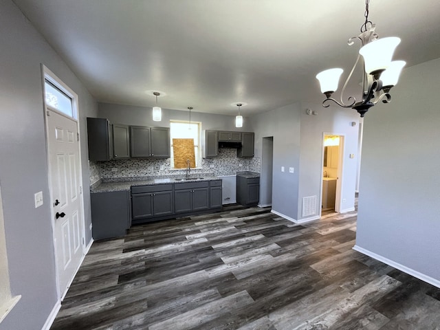 kitchen with sink, a notable chandelier, dark wood-type flooring, gray cabinets, and decorative backsplash