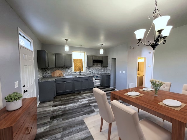 dining area featuring dark hardwood / wood-style floors, sink, and an inviting chandelier