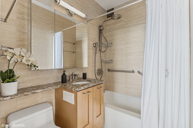 full bathroom featuring vanity, toilet, shower / bath combo with shower curtain, and tile walls