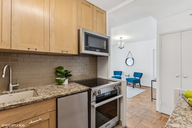 kitchen featuring light stone countertops, sink, appliances with stainless steel finishes, and tasteful backsplash