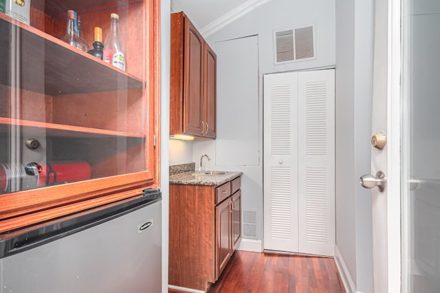 kitchen with stone counters, sink, ornamental molding, dark hardwood / wood-style floors, and stainless steel refrigerator