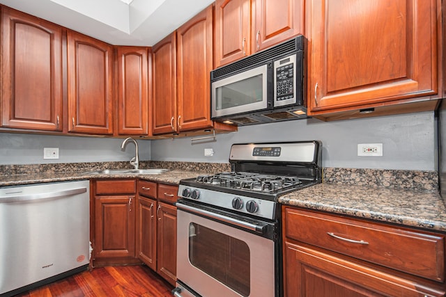 kitchen with dark hardwood / wood-style flooring, dark stone countertops, sink, and appliances with stainless steel finishes