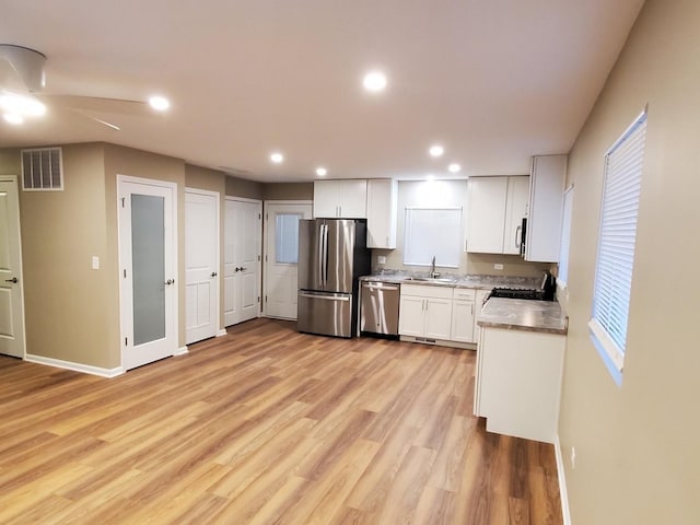 kitchen with sink, light hardwood / wood-style floors, white cabinets, and appliances with stainless steel finishes