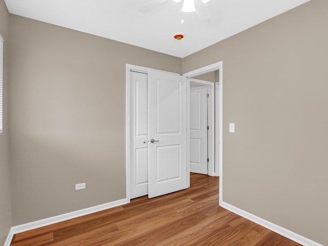 unfurnished bedroom with hardwood / wood-style flooring, ceiling fan, and a closet