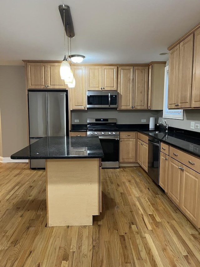 kitchen with a center island, light hardwood / wood-style flooring, dark stone counters, decorative light fixtures, and appliances with stainless steel finishes