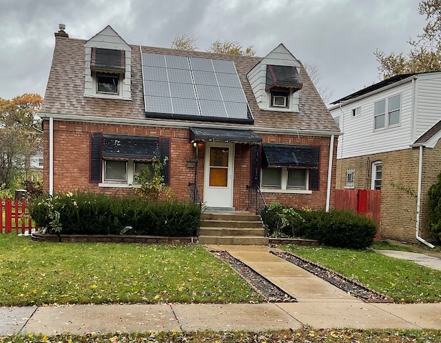 view of front of property featuring solar panels and a front lawn