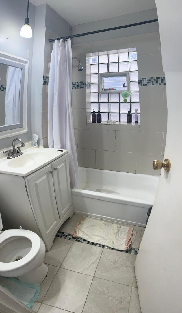 full bathroom with shower / bath combo with shower curtain, vanity, tile patterned floors, and toilet