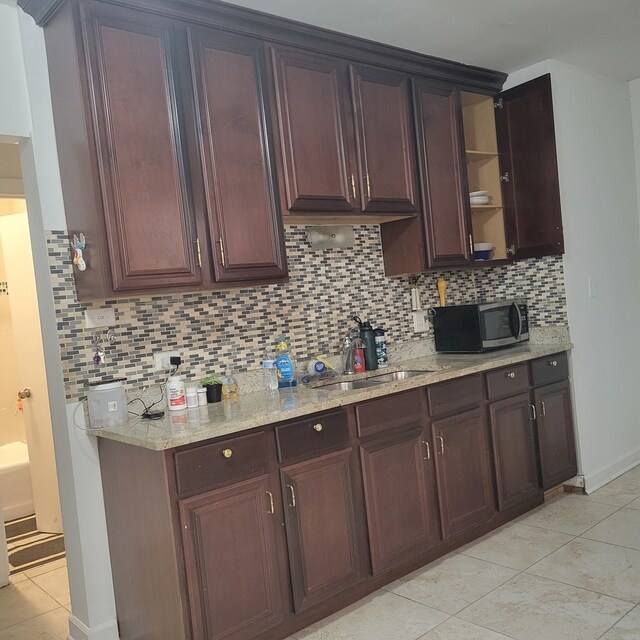 kitchen featuring light stone countertops, sink, light tile patterned flooring, and tasteful backsplash