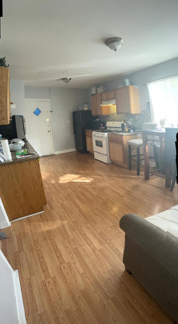 kitchen featuring black fridge, white range with gas cooktop, backsplash, and light hardwood / wood-style floors