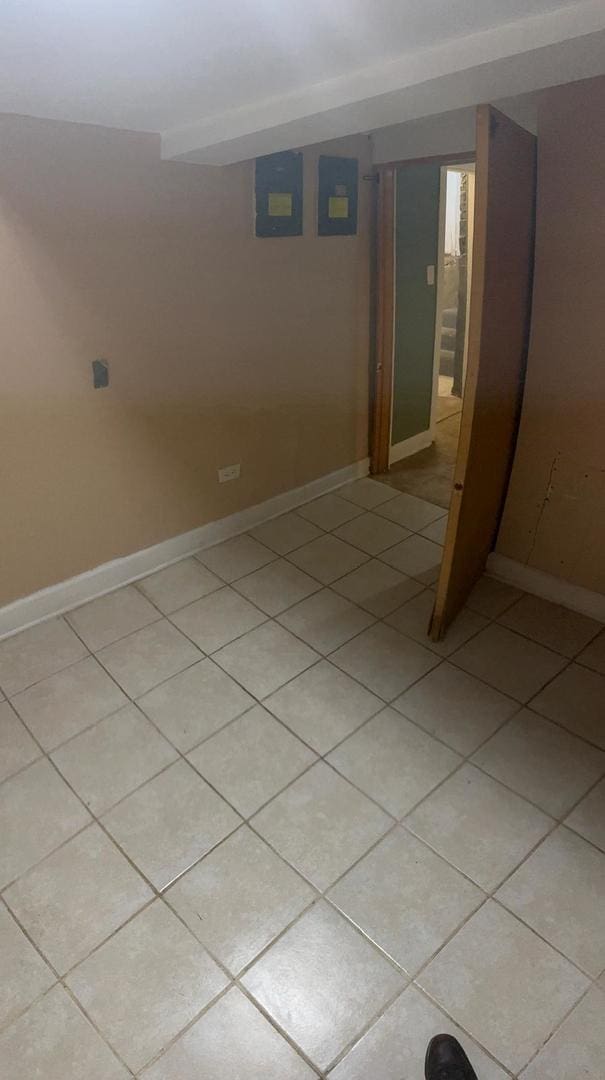 basement featuring electric panel and light tile patterned flooring