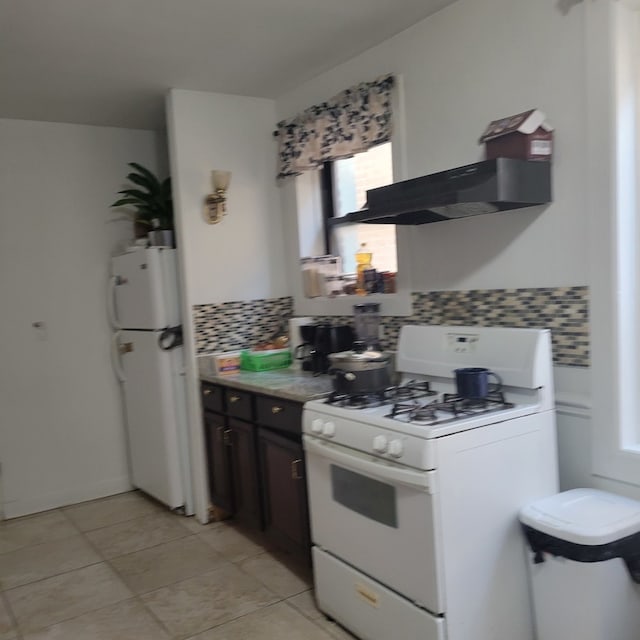 kitchen with light tile patterned floors, dark brown cabinets, backsplash, extractor fan, and white appliances