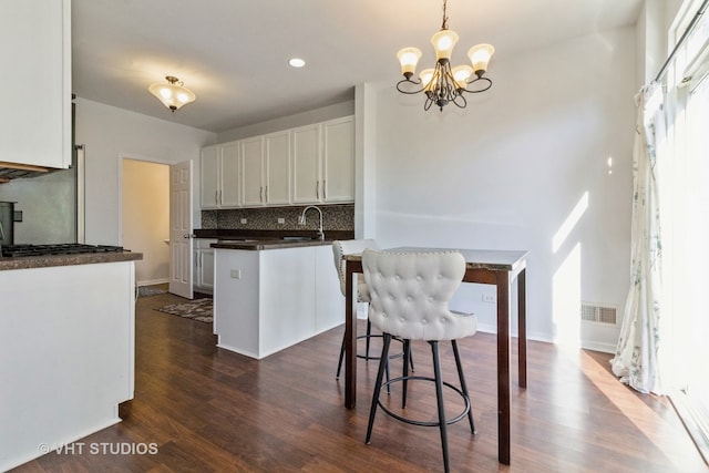 kitchen featuring hanging light fixtures, dark hardwood / wood-style floors, white cabinetry, and sink