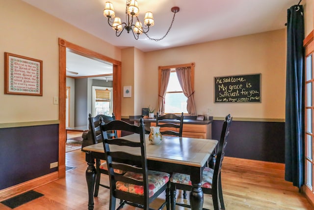 dining room with light hardwood / wood-style flooring and an inviting chandelier