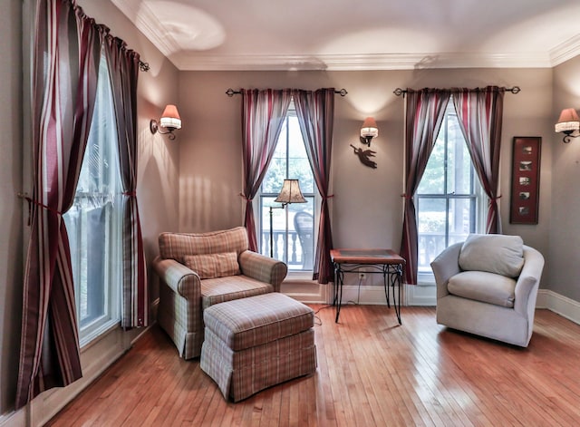 sitting room with ornamental molding and light wood-type flooring