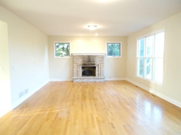 unfurnished living room featuring a brick fireplace and hardwood / wood-style flooring