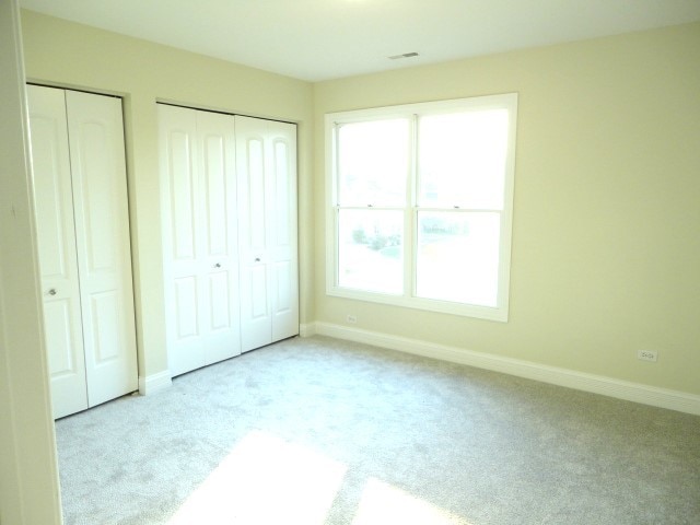 unfurnished bedroom with light carpet and two closets