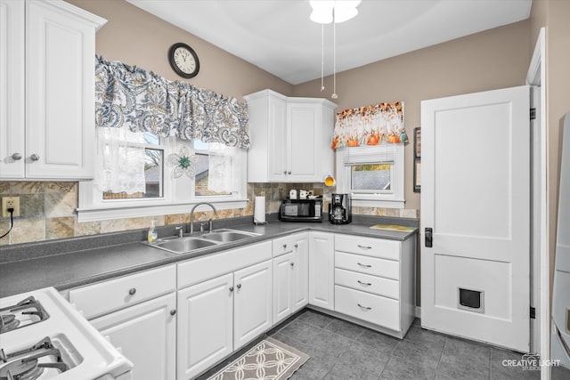 kitchen with white cabinets, decorative backsplash, sink, and white stove